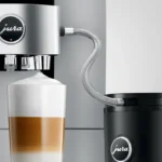 JURA coffee machine using a milk pipe with stainless steel casing to prepare a layered latte macchiato from a milk container.